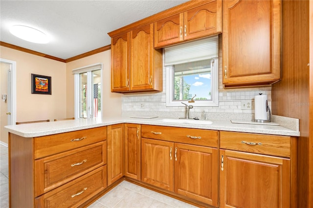 kitchen with backsplash, ornamental molding, sink, and light tile floors