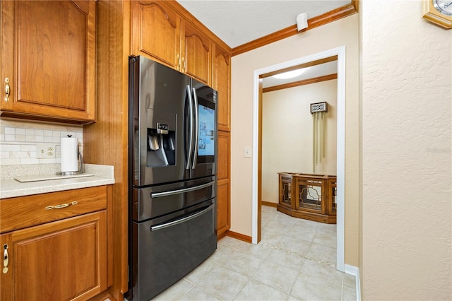 kitchen featuring light tile floors, backsplash, black fridge, and ornamental molding