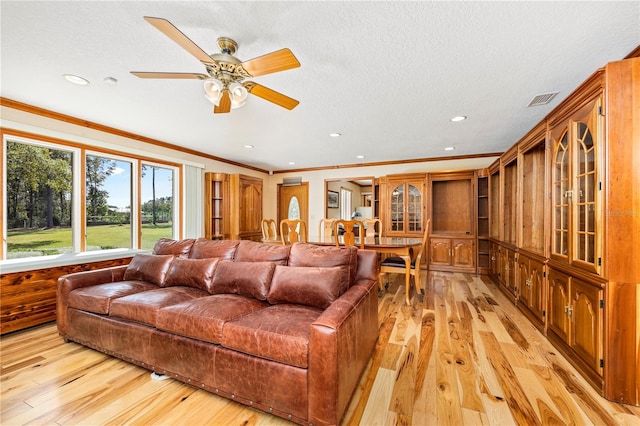 living room with ornamental molding, a textured ceiling, ceiling fan, and light hardwood / wood-style flooring