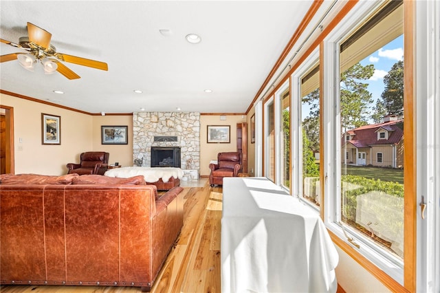 living room with light hardwood / wood-style floors, ceiling fan, a wealth of natural light, and a fireplace