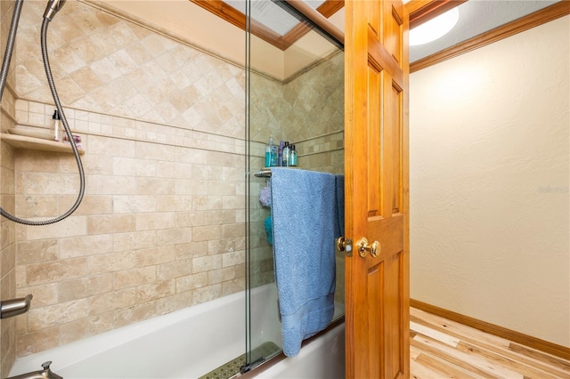 bathroom featuring ornamental molding and bath / shower combo with glass door