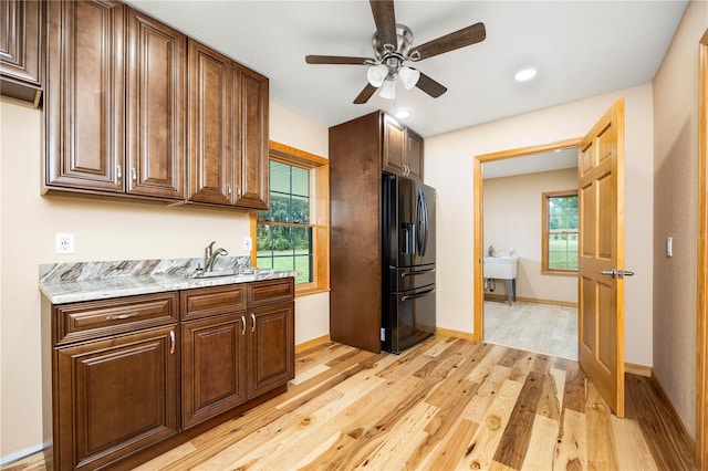 kitchen featuring stainless steel fridge with ice dispenser, ceiling fan, a wealth of natural light, and light hardwood / wood-style flooring