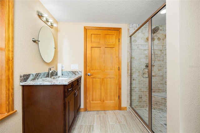 bathroom featuring tile floors, large vanity, walk in shower, and a textured ceiling