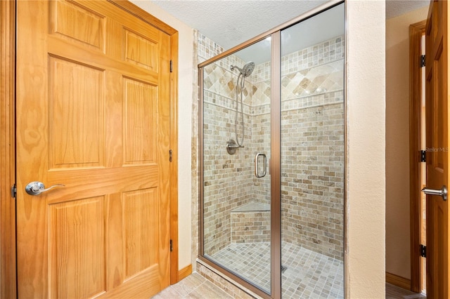 bathroom featuring tile flooring, an enclosed shower, and a textured ceiling