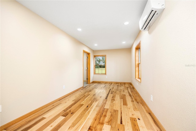 unfurnished room featuring a wall mounted air conditioner and light hardwood / wood-style floors