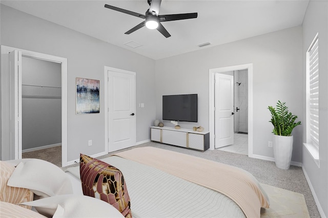 bedroom with a closet, ceiling fan, a walk in closet, ensuite bath, and light tile floors