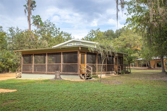 rear view of property with a lawn and a sunroom