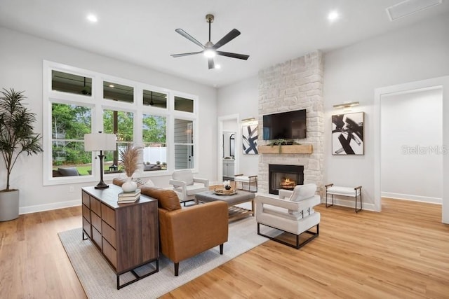 living room with a fireplace, ceiling fan, and light hardwood / wood-style flooring