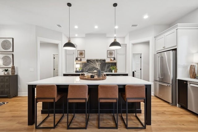 kitchen featuring appliances with stainless steel finishes, a breakfast bar, white cabinetry, and a spacious island