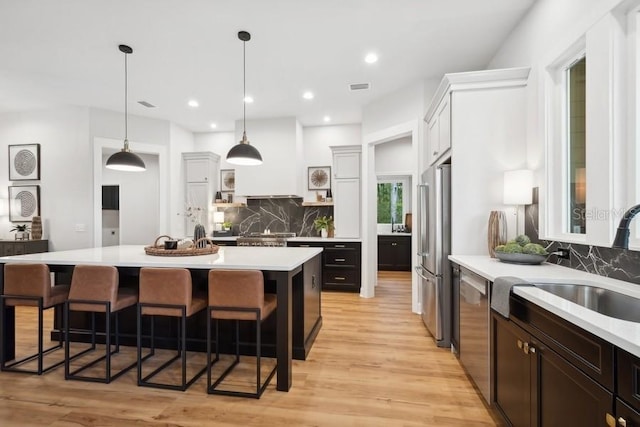 kitchen featuring white cabinets, a kitchen breakfast bar, tasteful backsplash, and stainless steel appliances