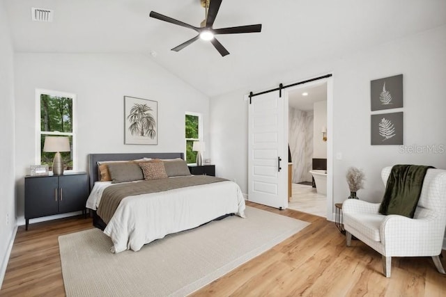 bedroom with ceiling fan, ensuite bath, a barn door, and wood-type flooring