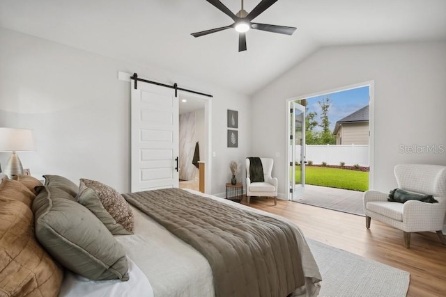 bedroom featuring vaulted ceiling, access to outside, hardwood / wood-style floors, ceiling fan, and a barn door