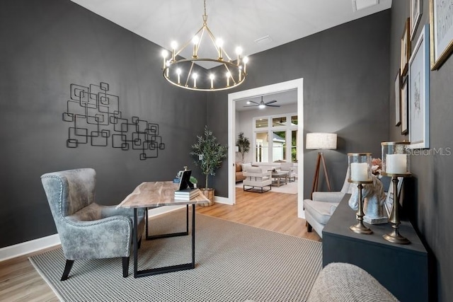 sitting room with ceiling fan with notable chandelier and wood-type flooring