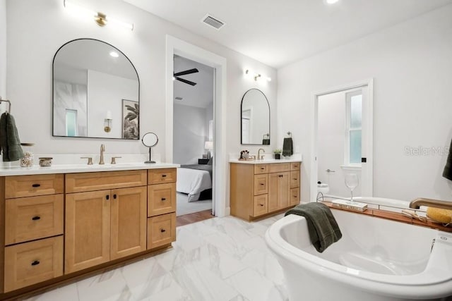 bathroom featuring toilet, ceiling fan, a bath, and vanity