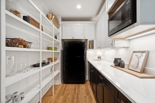 kitchen featuring black appliances, light wood-type flooring, and white cabinets