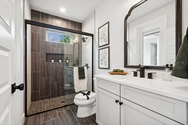 bathroom featuring toilet, vanity, and a shower with shower door