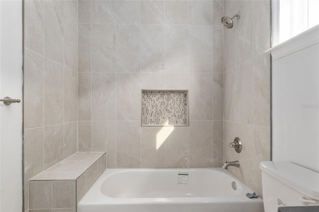 bathroom featuring toilet and tiled shower / bath