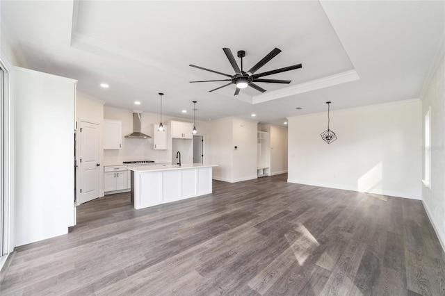 unfurnished living room featuring a tray ceiling, ceiling fan, sink, dark hardwood / wood-style flooring, and ornamental molding