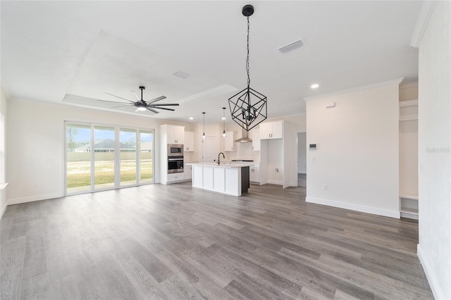 unfurnished living room with sink, ceiling fan with notable chandelier, and dark hardwood / wood-style flooring