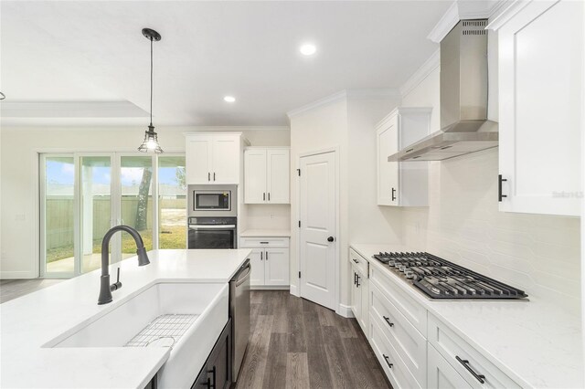 kitchen featuring white cabinetry, dark wood-type flooring, appliances with stainless steel finishes, wall chimney exhaust hood, and pendant lighting