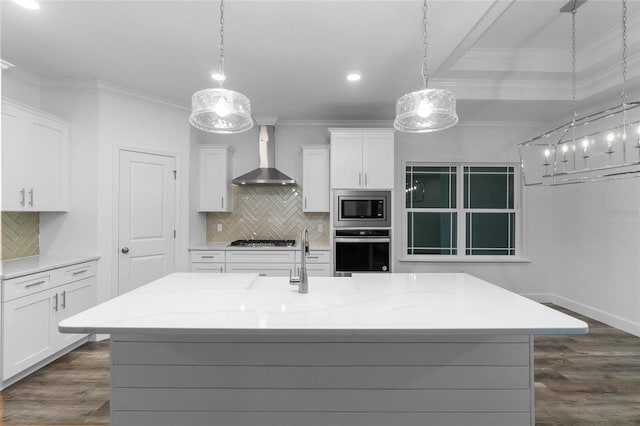 kitchen featuring wall chimney exhaust hood, pendant lighting, tasteful backsplash, and appliances with stainless steel finishes