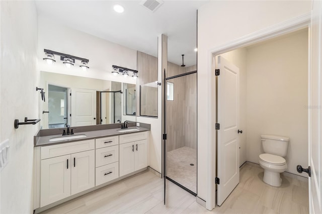 bathroom featuring toilet, vanity with extensive cabinet space, dual sinks, tile floors, and a tile shower