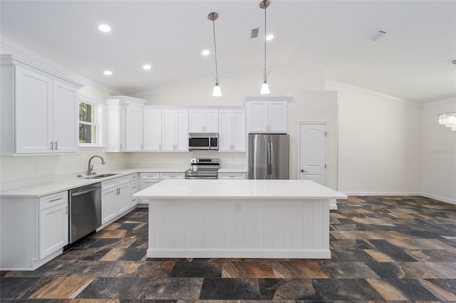 kitchen featuring dark tile patterned floors, crown molding, a center island, vaulted ceiling, and appliances with stainless steel finishes