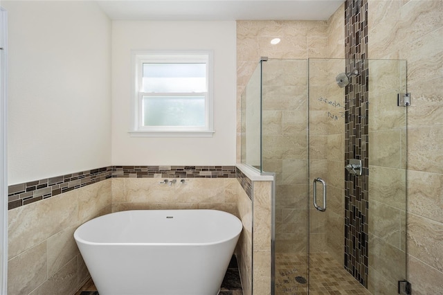 bathroom featuring plus walk in shower and tile walls