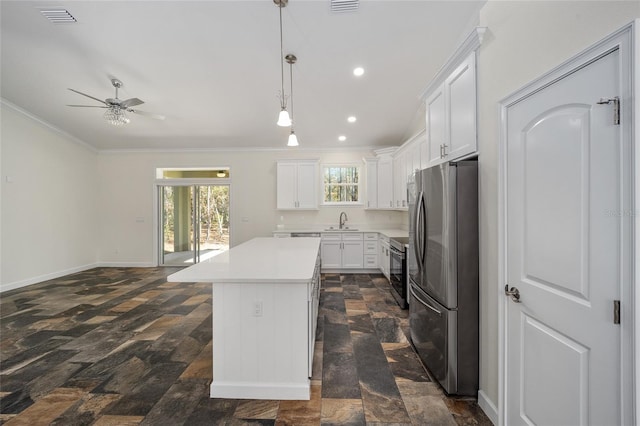 kitchen featuring white cabinets, sink, stainless steel refrigerator, a center island, and ceiling fan