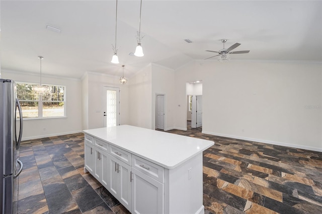 kitchen featuring dark tile patterned floors, crown molding, a center island, ceiling fan with notable chandelier, and stainless steel fridge