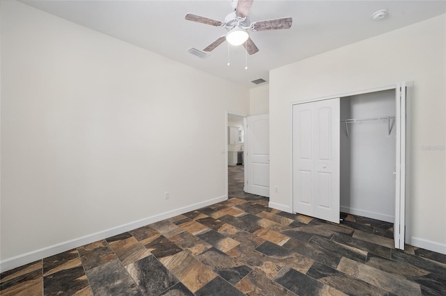 unfurnished bedroom with a closet, dark tile patterned floors, and ceiling fan