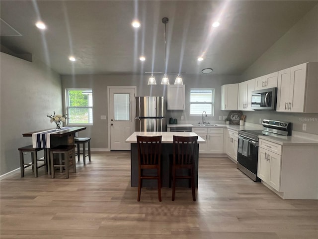 kitchen featuring a kitchen island, sink, light wood-type flooring, a breakfast bar area, and stainless steel appliances