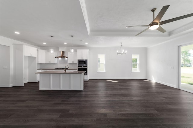 kitchen with appliances with stainless steel finishes, dark hardwood / wood-style flooring, white cabinets, and an island with sink