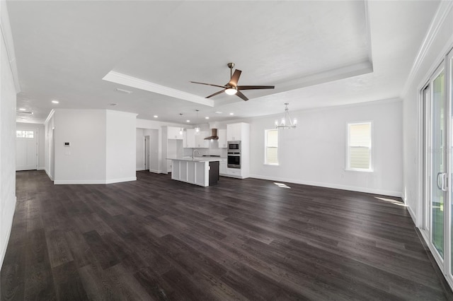 unfurnished living room with dark wood-type flooring, ornamental molding, a raised ceiling, and sink