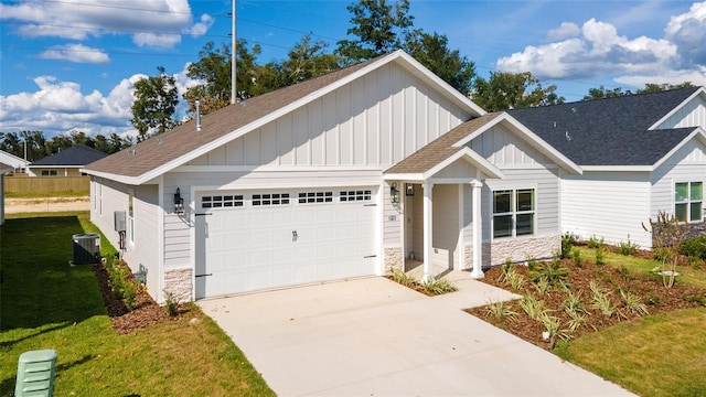 craftsman-style house with a garage, central air condition unit, and a front lawn