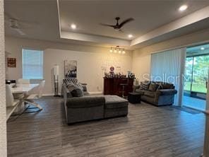 living room with dark hardwood / wood-style flooring, ceiling fan, and a tray ceiling