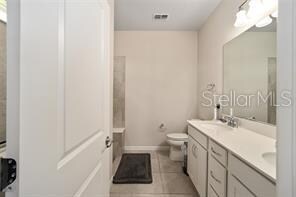 bathroom with double sink vanity, tile flooring, and toilet