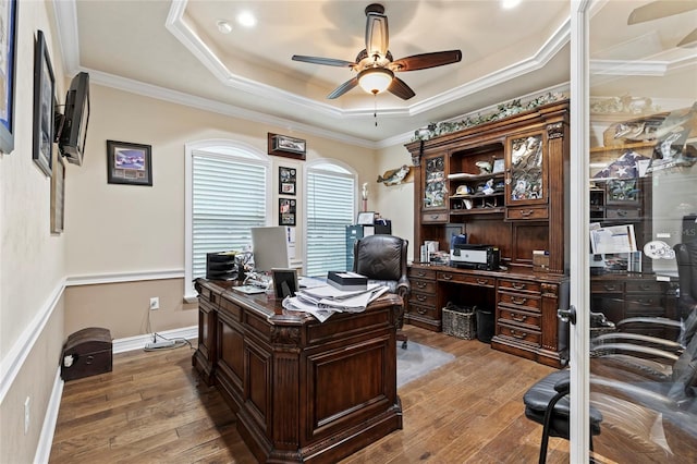 home office featuring a tray ceiling, ornamental molding, ceiling fan, and wood-type flooring