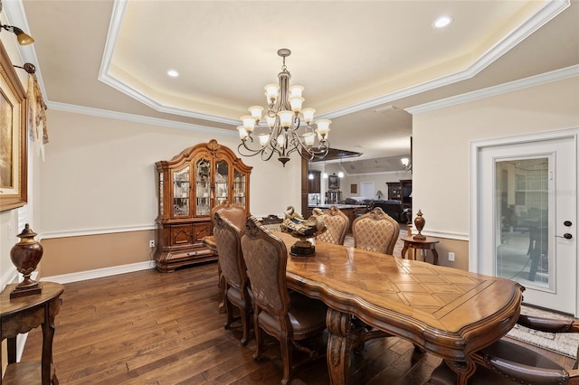 dining area featuring crown molding, a raised ceiling, dark wood-type flooring, and an inviting chandelier