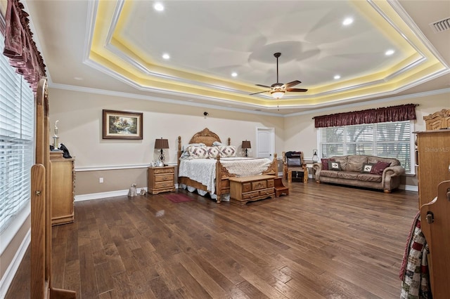 bedroom with dark hardwood / wood-style floors, ceiling fan, and a tray ceiling