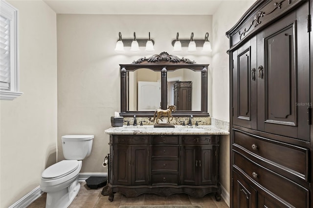 bathroom with oversized vanity, toilet, and double sink