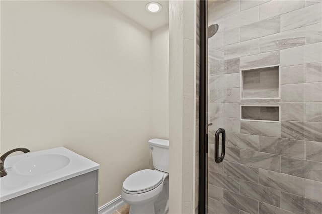 bathroom with toilet, vanity, and a shower with shower door