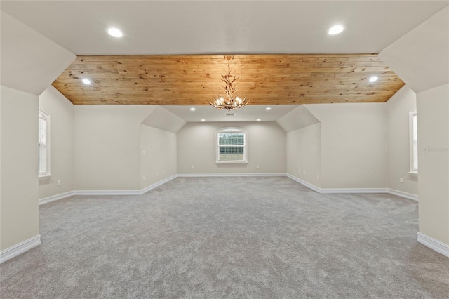 additional living space with lofted ceiling, light colored carpet, wooden ceiling, and an inviting chandelier