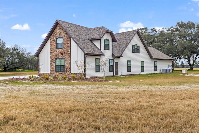 view of front of house with central AC unit and a front lawn