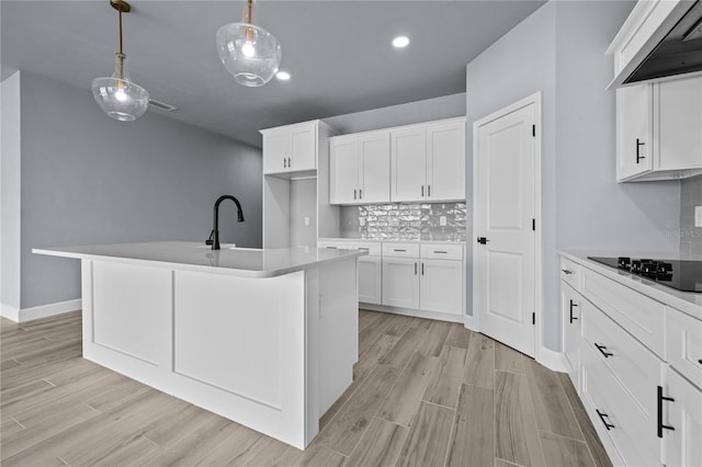 6624 SW 10th Ln, Gainesville, FL 32607 - kitchen with wall chimney exhaust hood, black electric stovetop, backsplash, hanging light fixtures, and white cabinets
