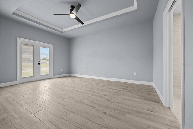 unfurnished room featuring light hardwood / wood-style flooring, a tray ceiling, ceiling fan, and french doors