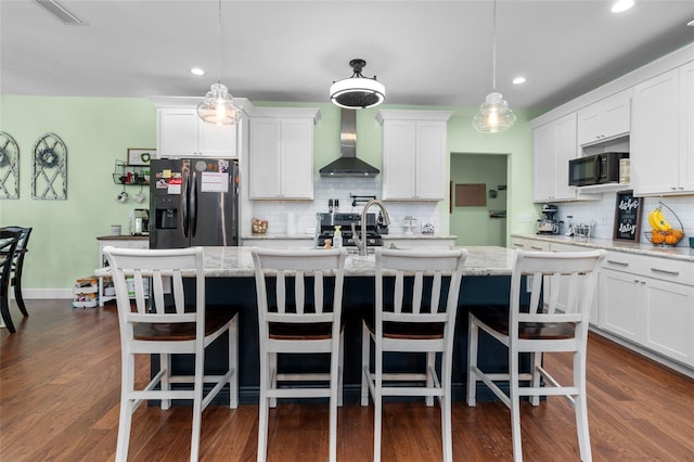 kitchen with wall chimney range hood, tasteful backsplash, stainless steel fridge, and decorative light fixtures