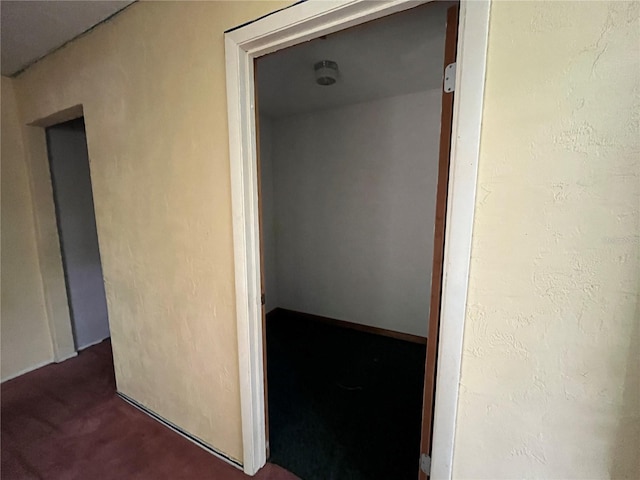 hallway with dark colored carpet