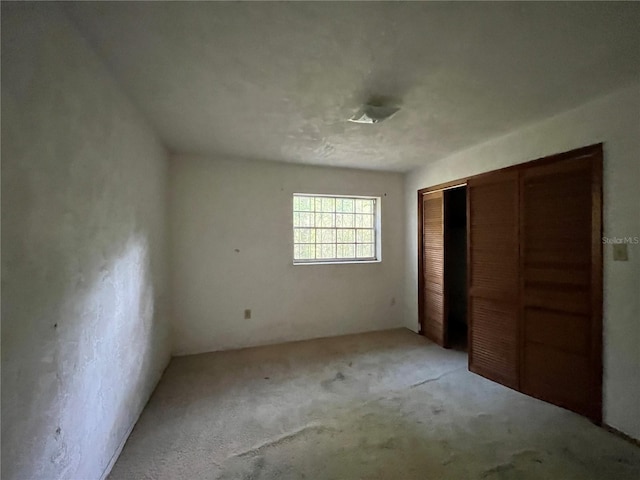 unfurnished bedroom featuring light carpet and a closet