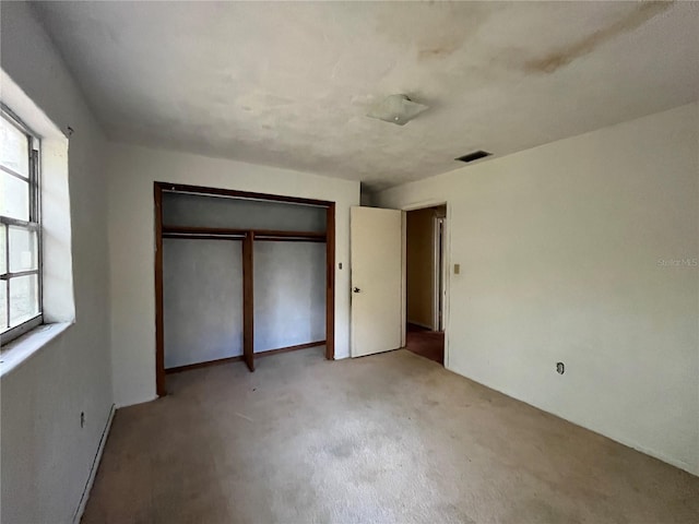 unfurnished bedroom with a closet and light carpet